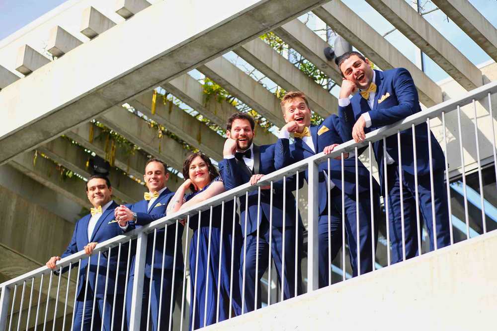 The boys and girl look down Groomsmen on balcony