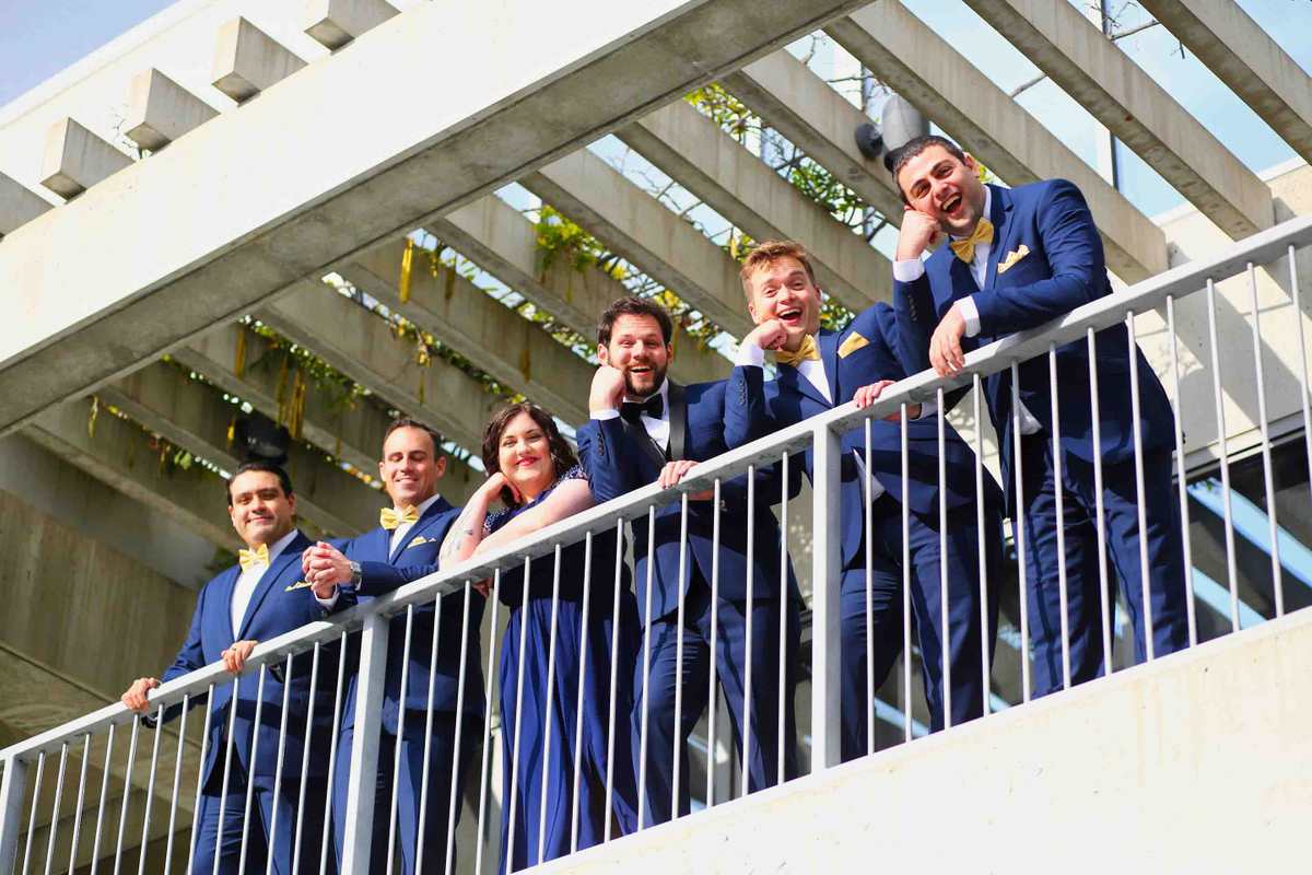 The boys and girl look down Groomsmen on balcony