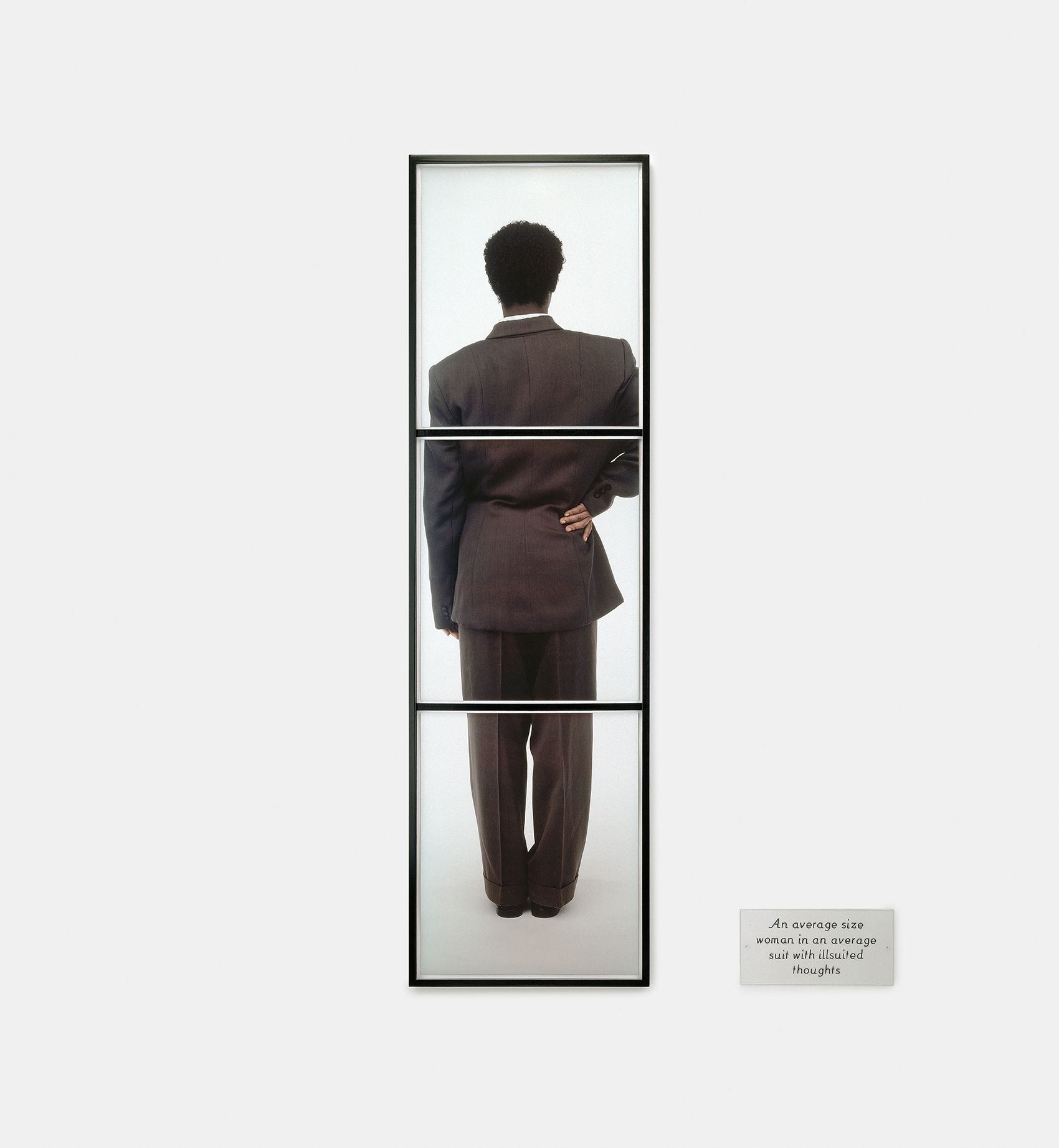 3 dye diffusion color Polaroid prints, 1 engraved plastic plaque - Overall: 76 x 44 1/2 in (193 x 113 cm), "Stretching across three panels, about six feet tall, in a business suit and short-cropped hair, it stands erect, a symbol of phallic power. This vertical axis of authority, however, is disturbed by a slight shift in the shoulders, the resting of hand on hip. Here is another classic pose: that of a black woman ready to give someone the business. As the plaque at right (the same side as the raised hand) states, she is: 'An average size woman in an average suit with illsuited thoughts.'" -Kellie Jones Suit, 1992