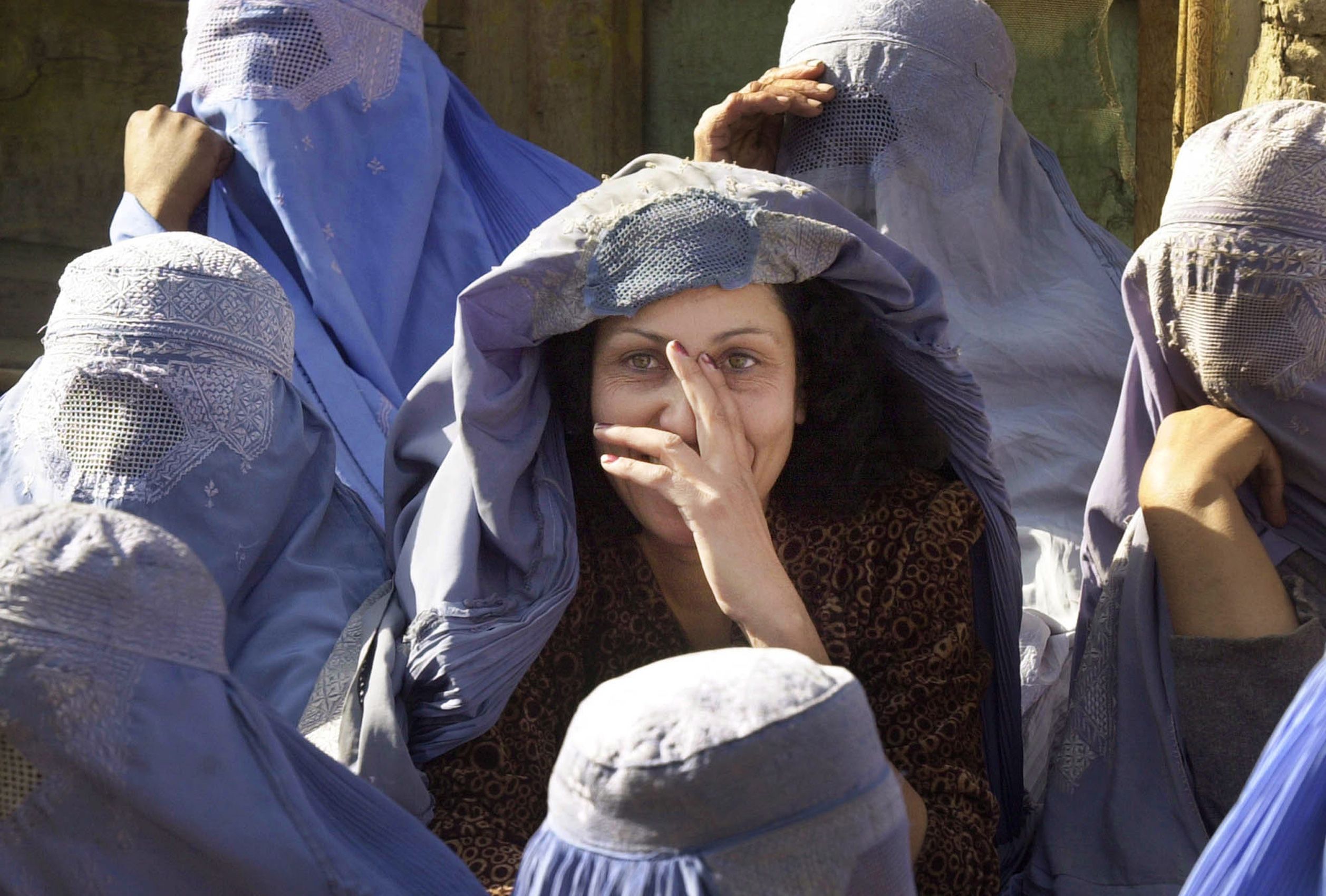 An Afghan widow, who chose to lift her burqa, smiles at the United Nations World Food Program bakery in Kabul, Afghanistan Wednesday, Nov. 21, 2001. About 350 widows, identified as the most vulnerable group in the city, received two cans of oil and two sacks of wheat from the United States Agency for International Development.  9/11 Afghanistan