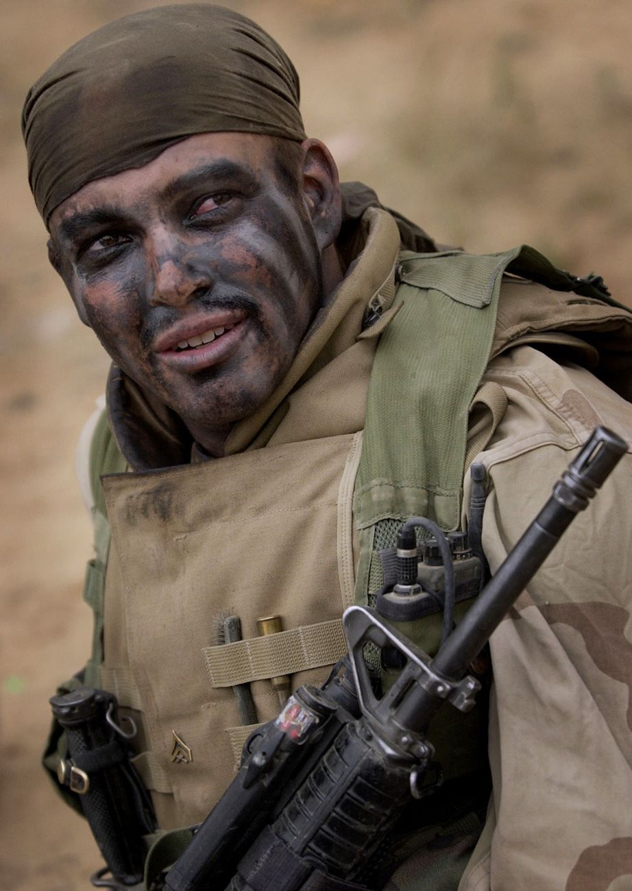 Cpl. Christopher Tate of Shawnee, Kan.,  with Kilo Co., 3rd Batt., 7th Marines, 1st Marine Division, sits covered with urban warfare paint while waiting for orders on the southeastern edge of Baghdad on Monday, April 7, 2003.  Invasion of Iraq