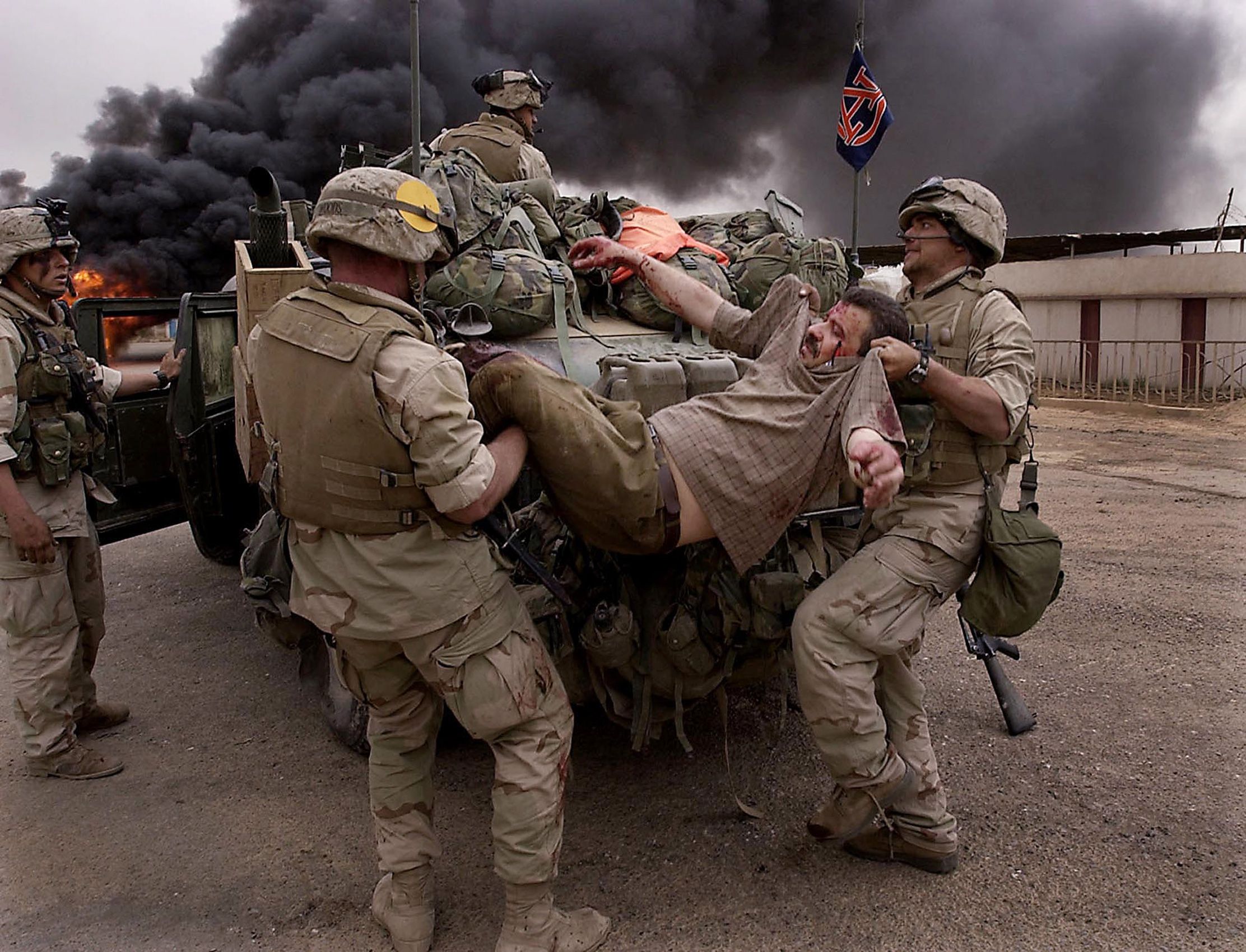 U.S. Marines with 3rd Batt., 7th Marines, 1st Marine Division load an injured Iraqi man on to their vehicle after the bus he was riding in came under fire as it entered a military compound that U.S. Marines had recently taken in southeast Baghdad on Tuesday, April 8, 2003. Invasion of Iraq