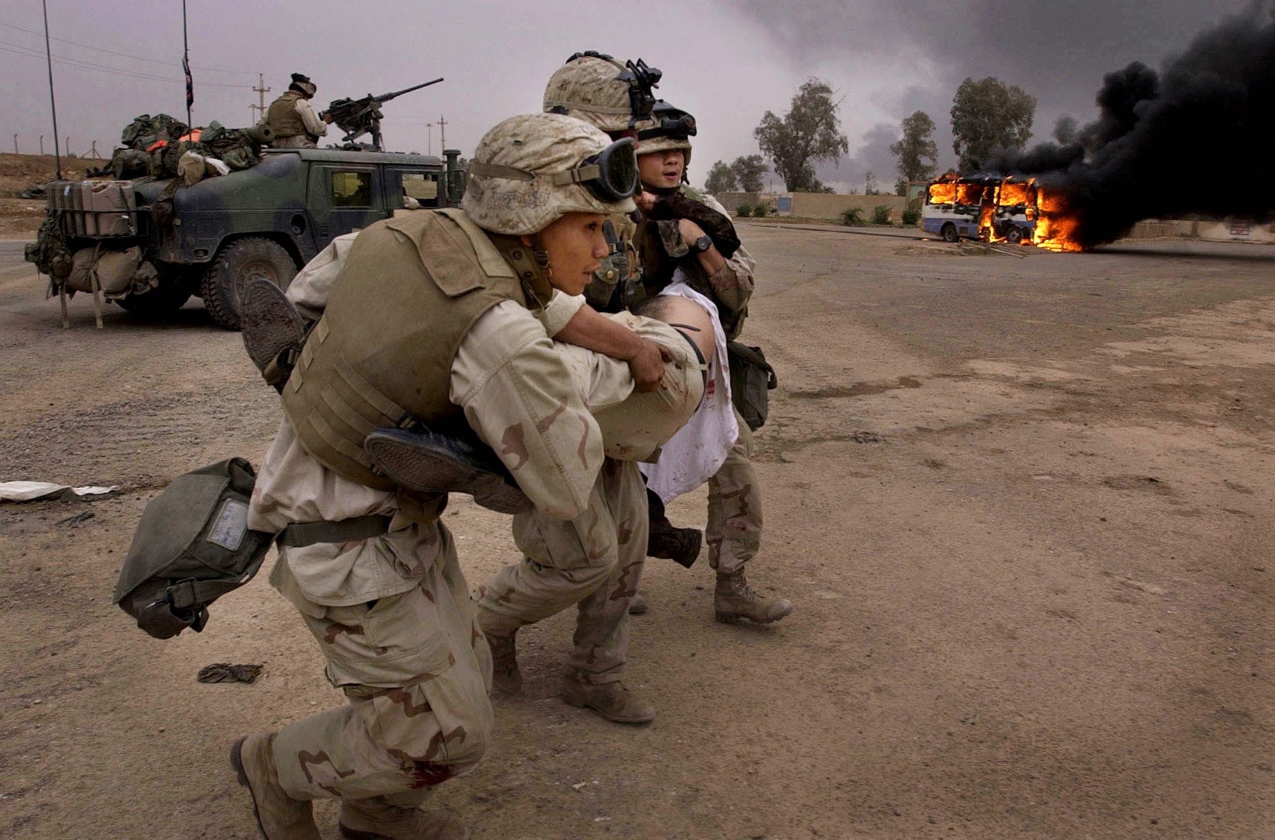 Navy corpsman carry an injured Iraqi man to a place to treat him after the bus he was riding in came under fire as it entered a military compound that U.S. Marines had recently taken in southeast Baghdad on Tuesday, April 8, 2003. Invasion of Iraq