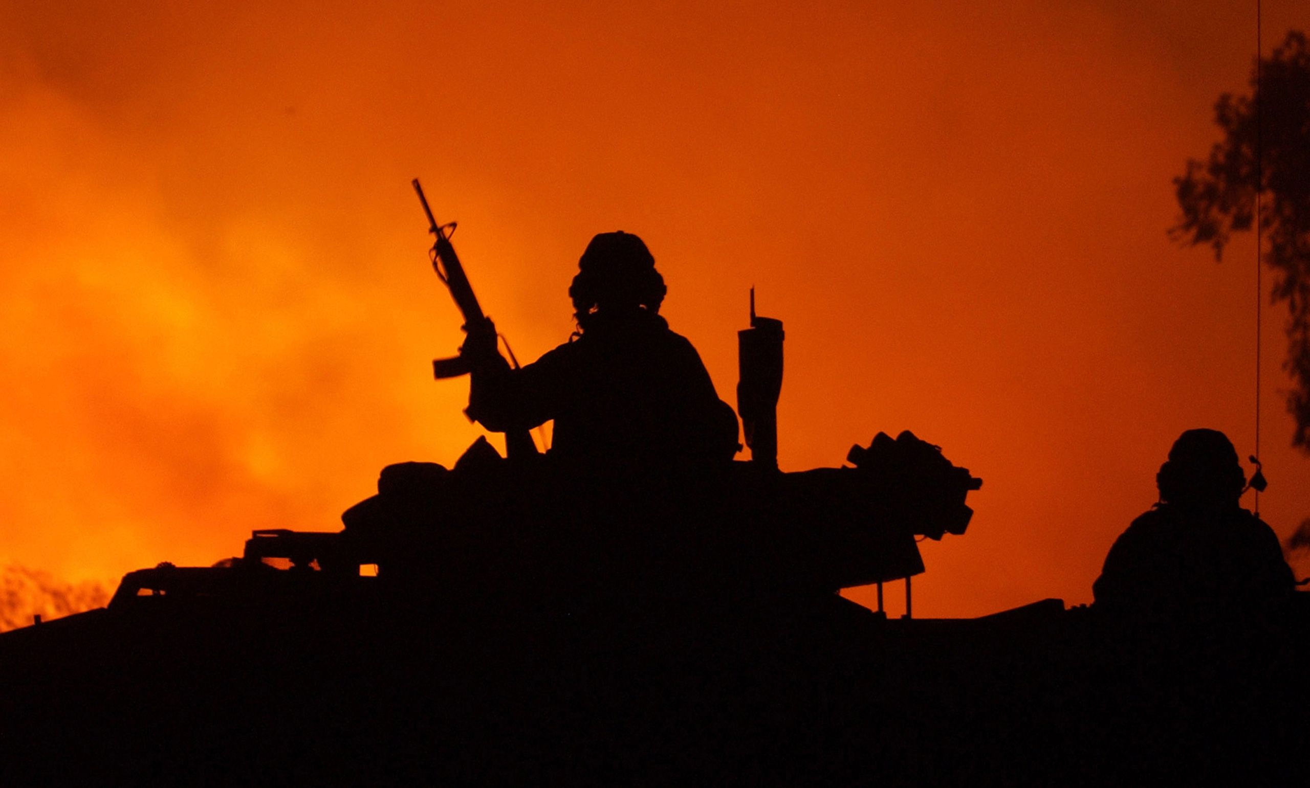 U.S. Marines with India Co., 3rd Batt., 7th Marines, watch as a fire rages following the air and artillery strike of an army training camp southeast of Baghdad on Sunday, March 6, 2003. Invasion of Iraq