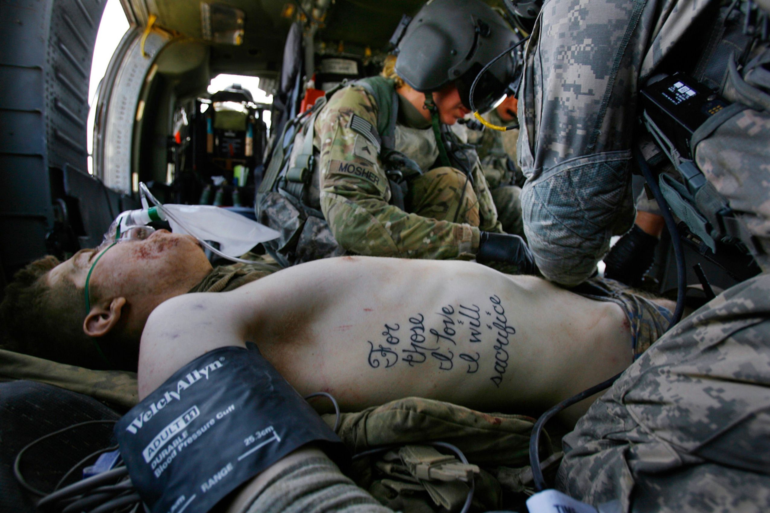 Pfc. Kyle Hockenberry, of 4th Squadron, 4th Cavalry Infantry Regiment, 1st Heavy Combat Brigade, 1st Infantry Division, who was injured in an improvised explosive device attack near Haji Ramuddin, is treated by flight medic Cpl. Amanda Mosher while being transported by medevac helicopter to the Role 3 hospital at Kandahar Air Field in Afghanistan on June 15, 2011. Throughout Hockenberry's multiple surgeries and skin grafts, doctors have worked around his tattoo and left it intact.  For Those I Love I Will Sacrifice