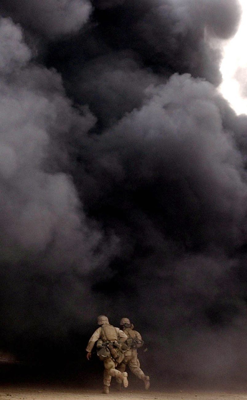 Marines with India Co., 3rd Batt., 7th Marines, 1st Marine Division, race into a wall of smoke as they advance on the headquarters of the Fidaeen in Baghdad on Wednesday, April 9, 2003. The Fidaeen are a secret fighting force controlled by Saddam Hussein. Invasion of Iraq