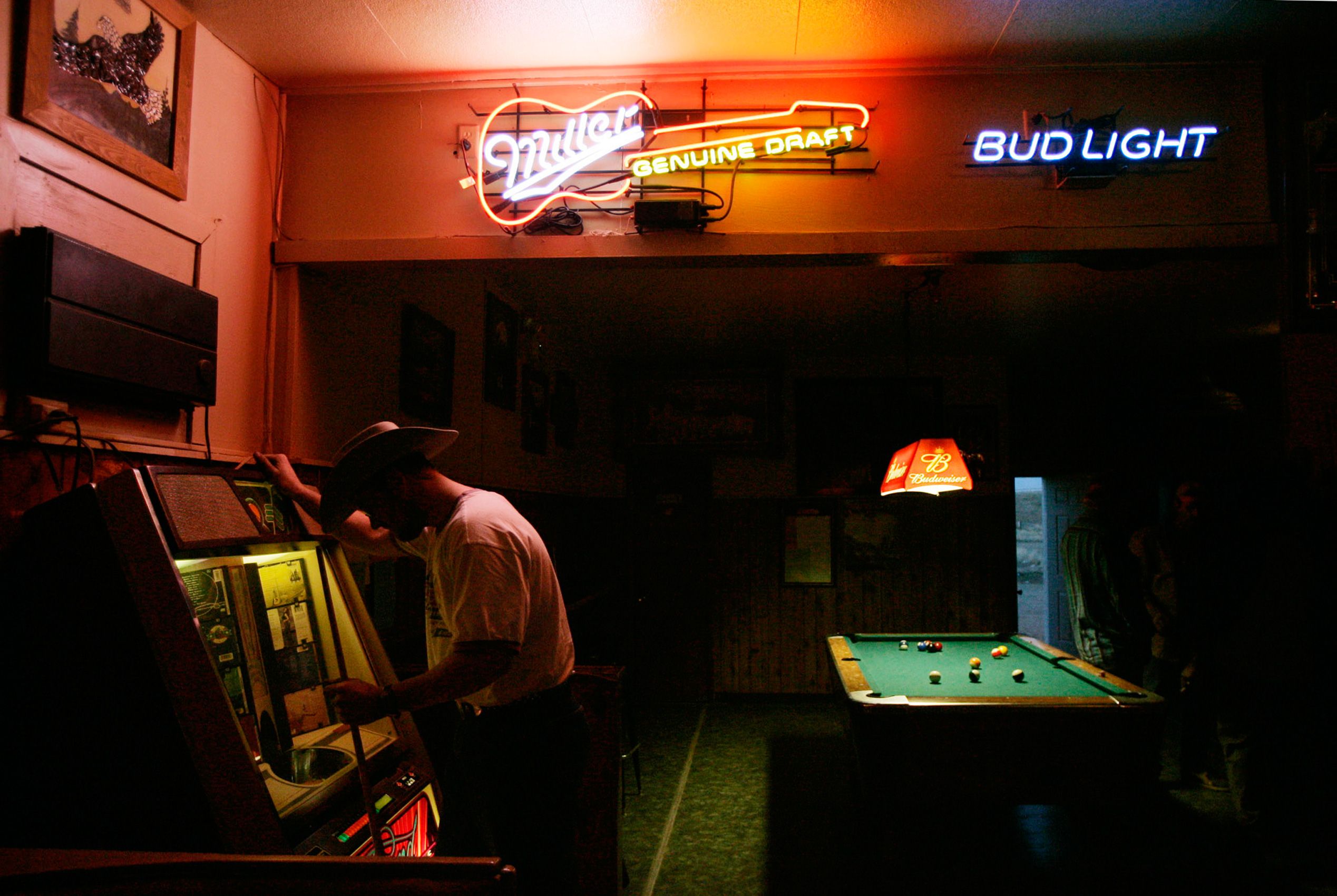 Gas field worker Matt Zupanik looks at the juke box while playing a game of pool at the town's only bar in Wamsutter, Wyo. on April 14, 2005. Wyoming Cowboys