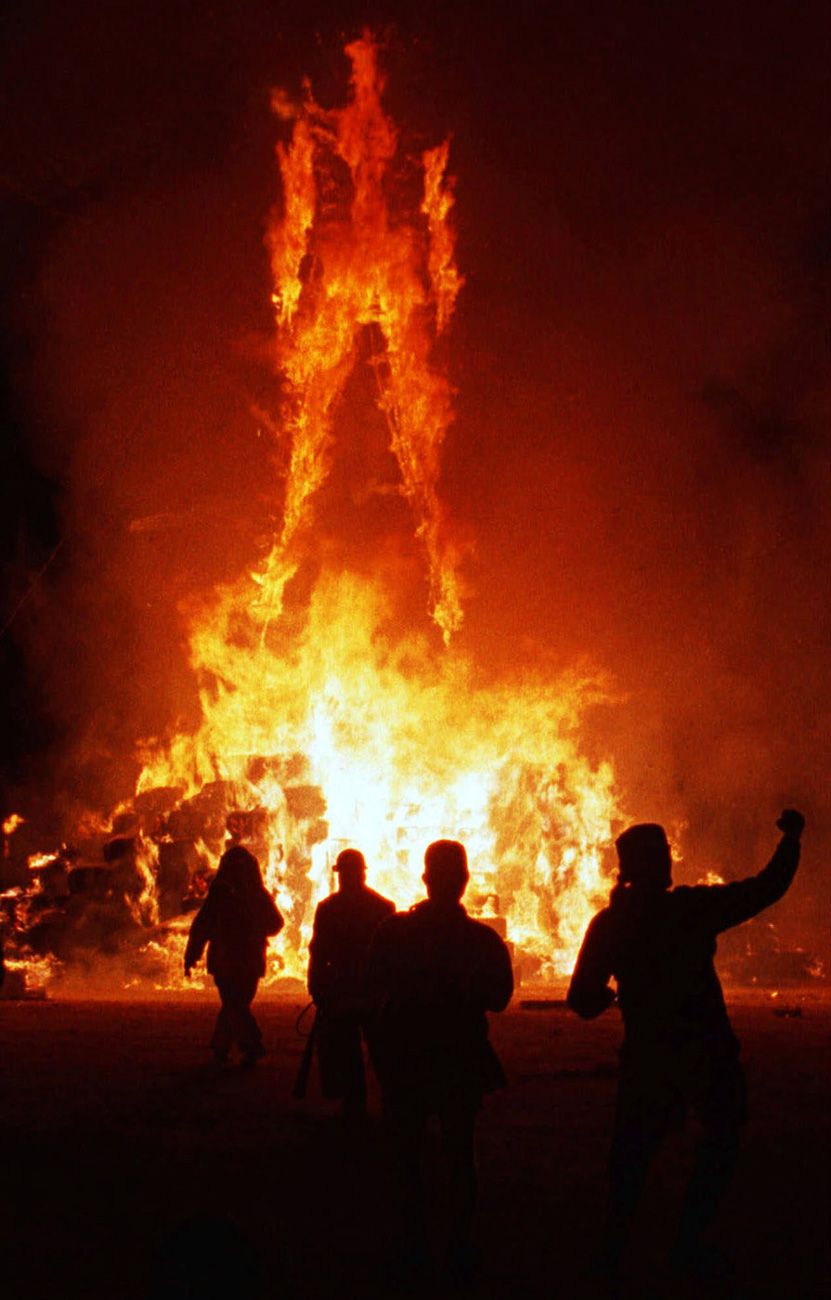 Spectators cheer as a 50-foot-high wooden effigy of a man is burned on the final day of the Burning Man festival near Gerlach, Nev., on Sept. 4, 1999.  Burning Man 1999