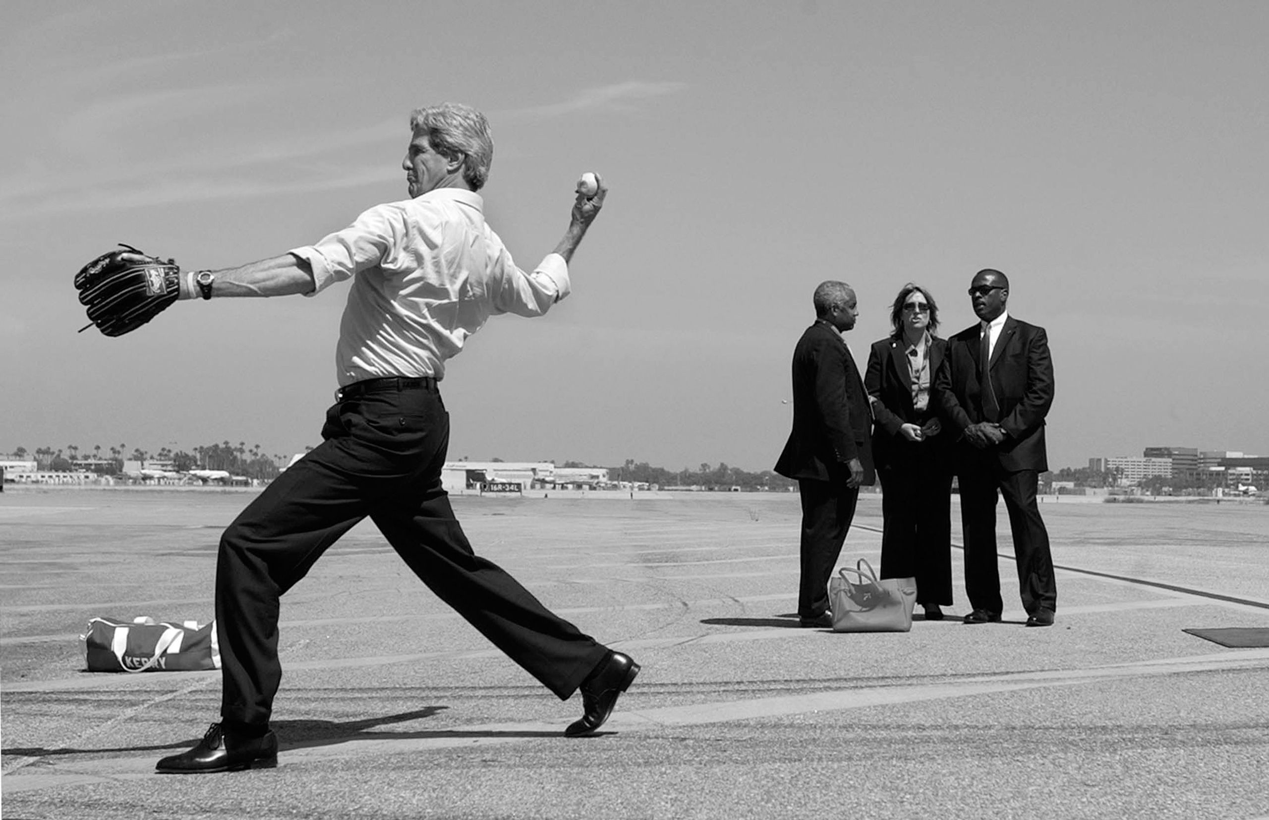 Democratic presidential nominee Sen. John Kerry, D-Mass., throws a ball while playing a game of catch on the tarmac as secret service agents stand by in Long Beach, Calif. on Thursday, Aug. 12, 2004. John Kerry Presidential Campaign 2004