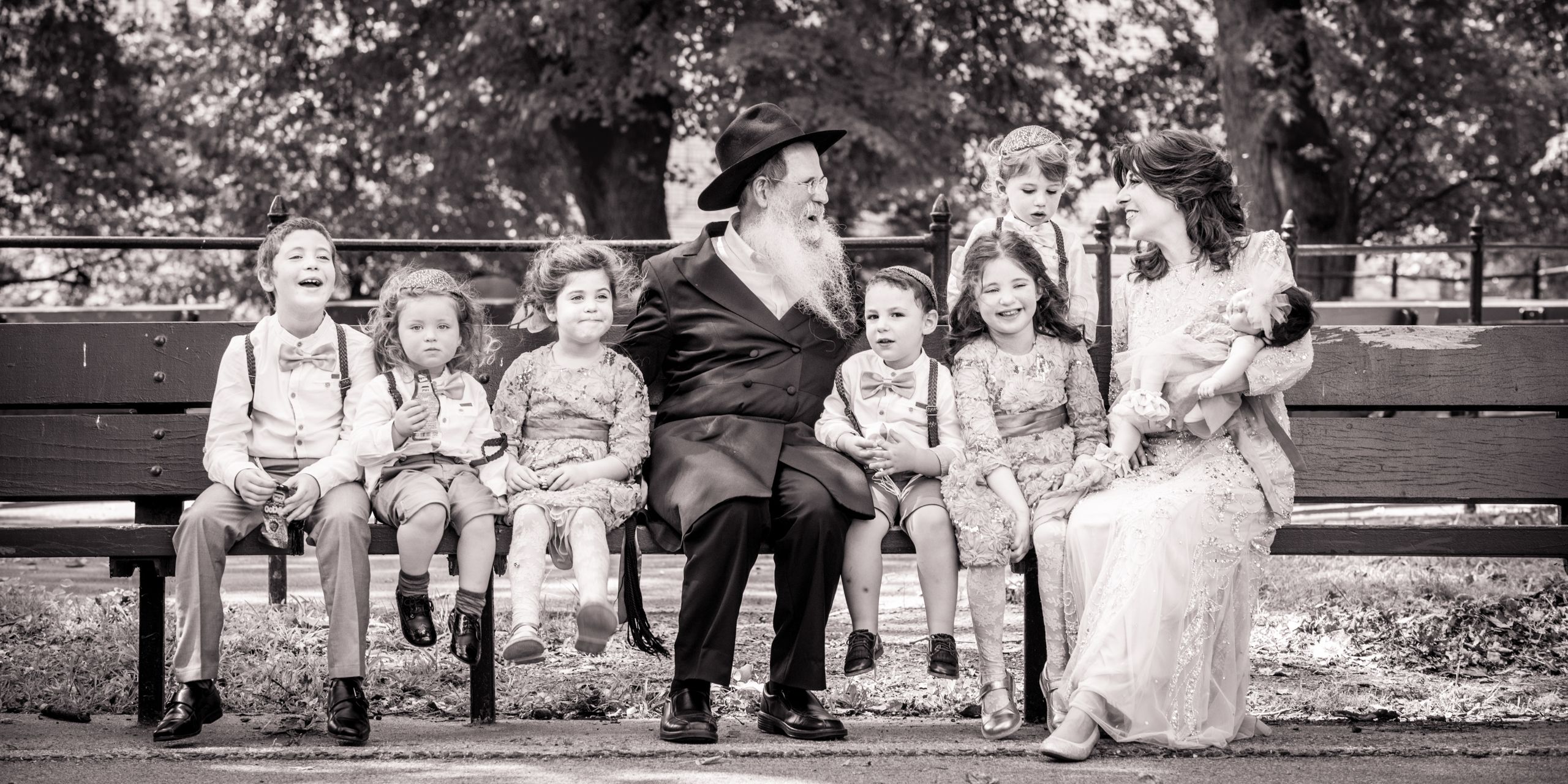 A candid moment of these gandparents sitting on a bench with their grandchildren between camera set ups.
