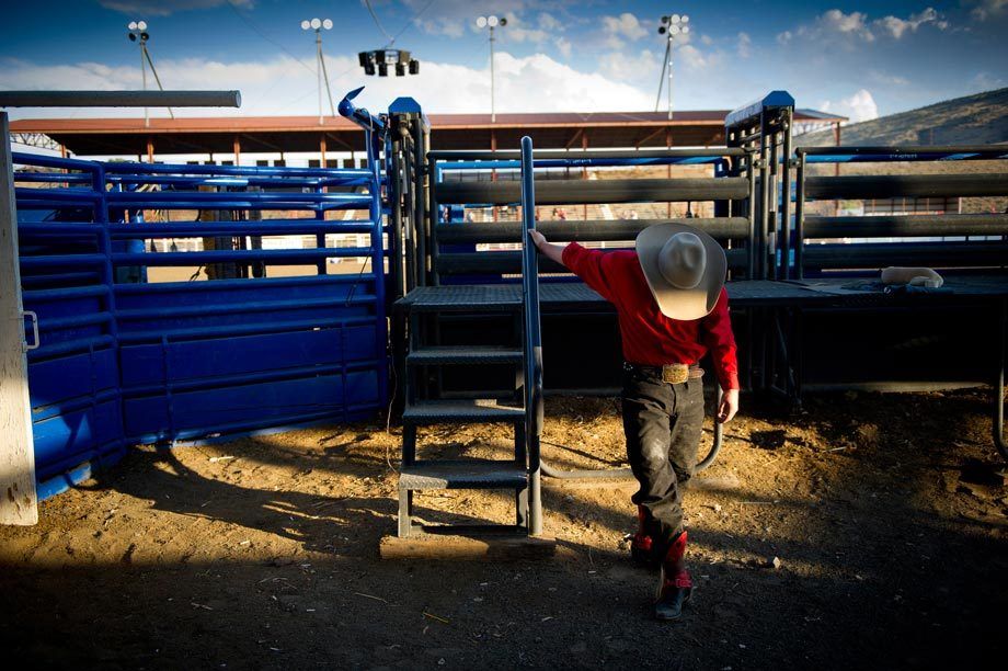 A cowboy stretches in the fading sunlight prior to the nightly rodeo in Cody, WY. Photographed for the New York Times. CODY RODEO