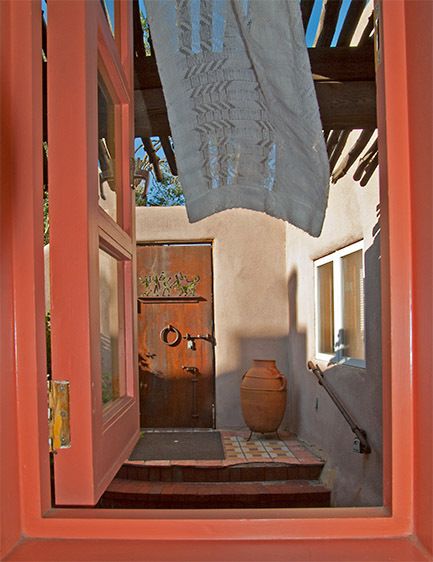 view out the window into a courtyard of old adobe house