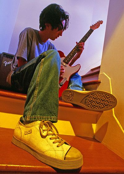 Teenage boy playing his Fender guitar with Fender shoes
