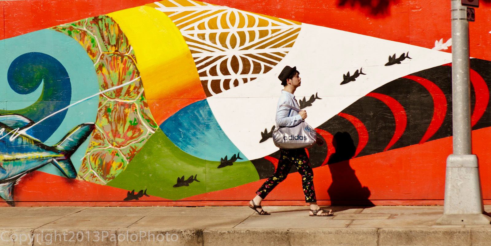 photograph by San Francisco advertising photographer PaoloPhoto of young man in Hawaii walking past wall mural-  paolophoto.com/fish/people/mural/Hawaii/photo.jpg Walk with the Fish- paolophoto.com/fish/people/photo.jpg