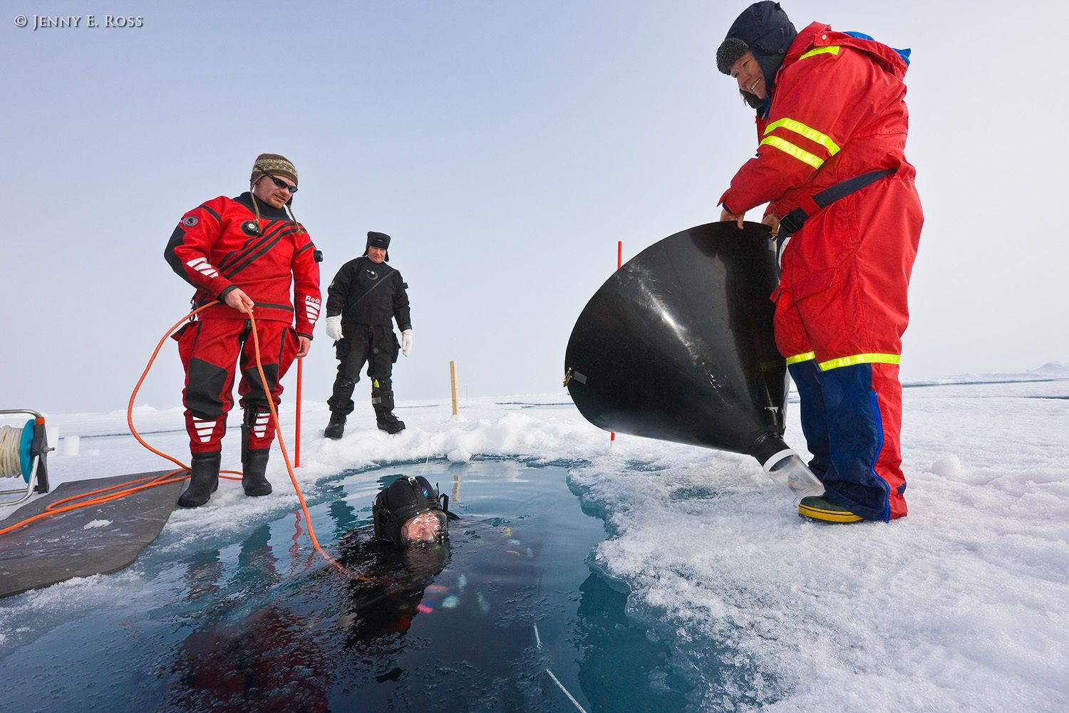 Norwegian Polar Institute scientific divers (Rupert Krapp in red on left, Michal Tessmann in black on the ice, Dr. Haakon Hop in the water) and scientist Dr. Agneta Fransson (in red on right) prepare for research activities that will take place beneath a large floe of sea ice in the Arctic Ocean during NPI's 2012 "ICE" (Ice, Climate, Ecosystems) expedition in July-August 2012. Scientific research on arctic sea ice, central polar basin, Arctic Ocean