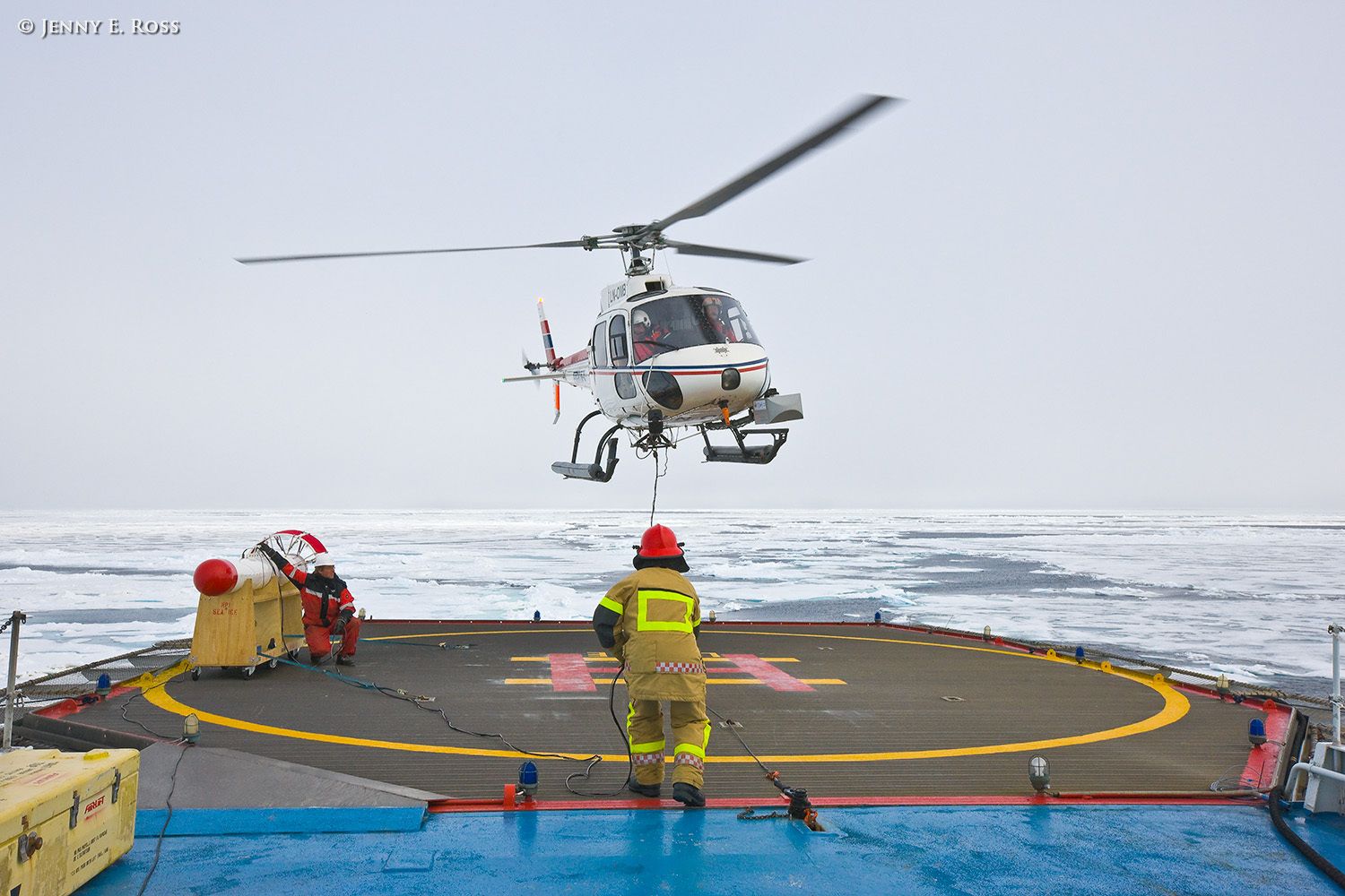On a research expedition in the Arctic Ocean, Norwegian Polar Institute scientists assessed sea ice thickness using an airborne instrument called the EM-Bird, a large torpedo-shaped scientific device. During helicopter transects flown above the ice, the electromagnetic and laser sensors in the EM-Bird collect data for use in calculating the thickness of the sea ice. This work was conducted on melting summer sea ice in the Arctic Ocean as part of NPI's 2012 "ICE" (Ice, Climate, and Ecosystems) expedition in July-August 2012. In this photograph, the helicopter carrying the EM-Bird is approaching the RV Lance to land on the ship after doing transects to collect data. Scientific research on arctic sea ice, central polar basin, Arctic Ocean