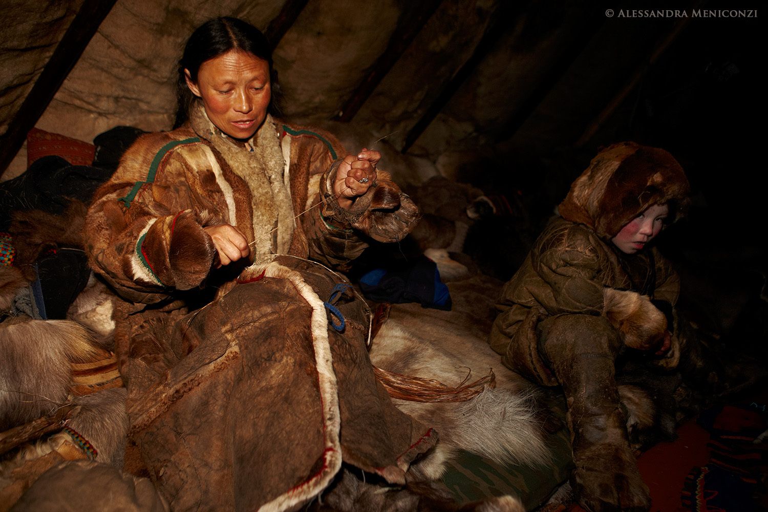 Yamal Peninsula, Siberia, Russian Federation. A Nenet woman sewing inside her family's chum.