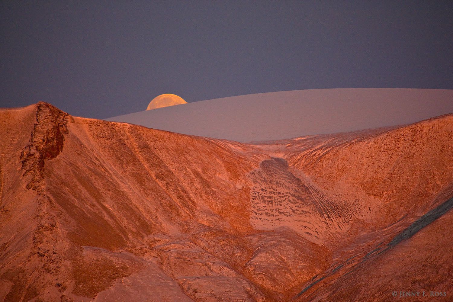 The full moon rises at sunset behind a portion of the Greenland Ice Sheet that has receded away from the coast of Northwest Greenland. Scars in the rock reveal where a glacier previously scoured a trough from the ice sheet to the sea.