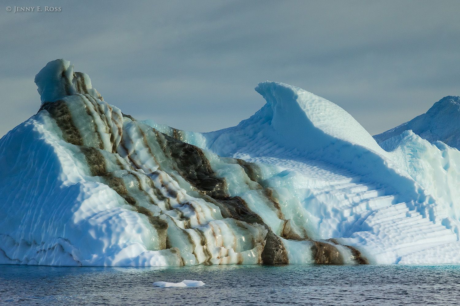 A large iceberg with very unusual stripes containing layers of ancient sediments, in Red Fjord (Rode Fjord), Scoresby Sund, East Greenland.