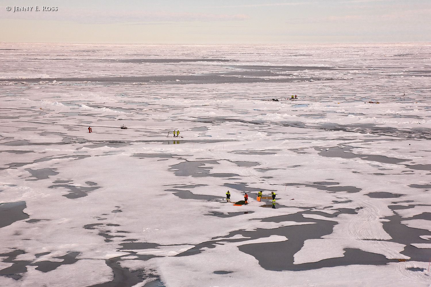 Norwegian Polar Institute scientists conducting research on sea ice in the Arctic Ocean during NPI's 2012 "ICE" (Ice, Climate, and Ecosystems) expedition in July-August 2012. The areas of water are shallow melt ponds of varying depth on the surface of the ice floe. Lines of broken ice chunks across the image are pressure ridges in the floe. Scientific research on arctic sea ice, central polar basin, Arctic Ocean
