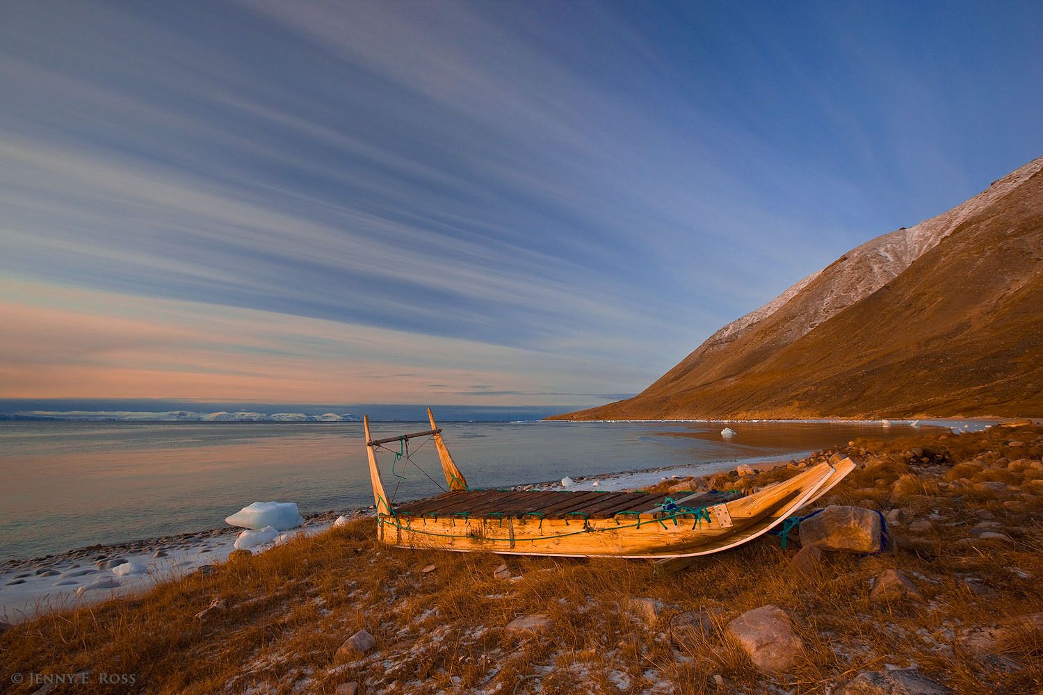 An Inuit sledge (dogsled), used for hunting with dog teams on the sea ice, lies idle near the shoreline of the unfrozen sea in Siorapaluk, Northwest Greenland.
