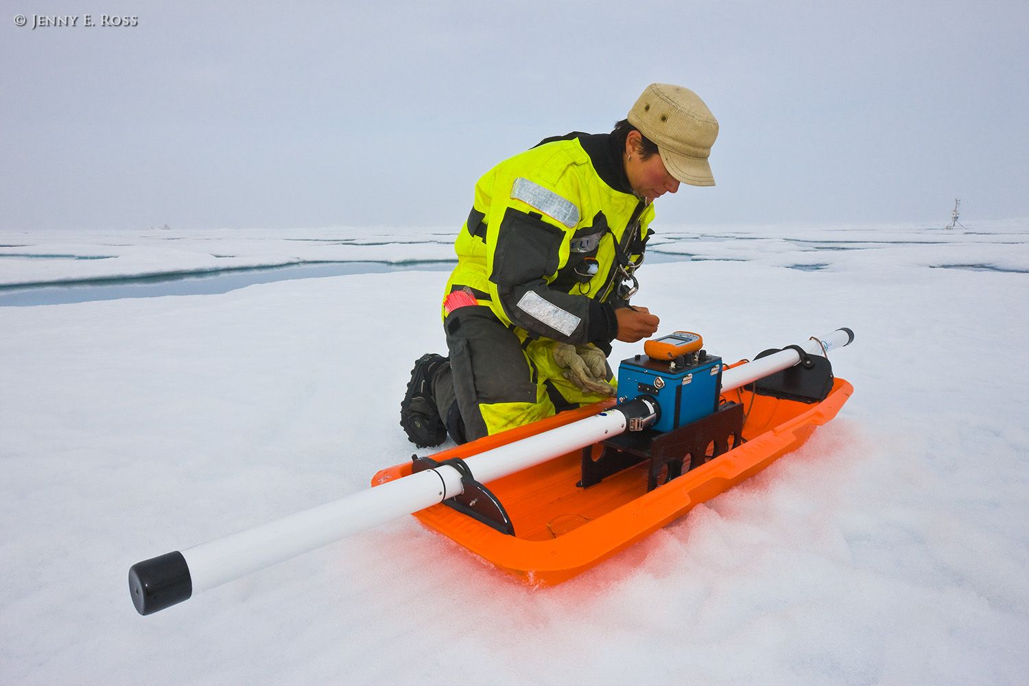 During a research expedition in the Arctic Ocean, Norwegian Polar Institute scientist Dr. Angelika Renner, a physical oceanographer and sea ice physicist, uses an electromagnetic instrument to collect data that will be used to calculate the thickness of the sea ice. The device is an EM-31, a ground-based version of the airborne EM-Bird instrument. This work was conducted on a large floe of melting summer sea ice in the Arctic Ocean as part of NPI's 2012 "ICE" (Ice, Climate, and Ecosystems) expedition in July-August 2012. The NPI research ship "RV Lance" was attached securely to this particular floe of ice, and the vessel moved with the floe as the ice floated freely in the ocean, for the duration of various on-ice research activities in July-August 2012. The areas of water in the photograph are shallow melt ponds of varying depth on the surface of the ice floe. Scientific research on arctic sea ice, central polar basin, Arctic Ocean