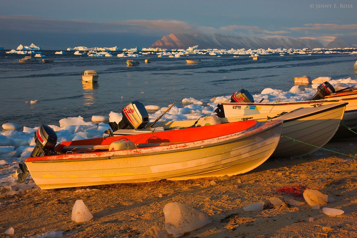 Small boats glow in the early morning light along the shoreline of Qaanaaq, at the edge of Murchison Sound in Baffin Bay, Northwest Greenland.