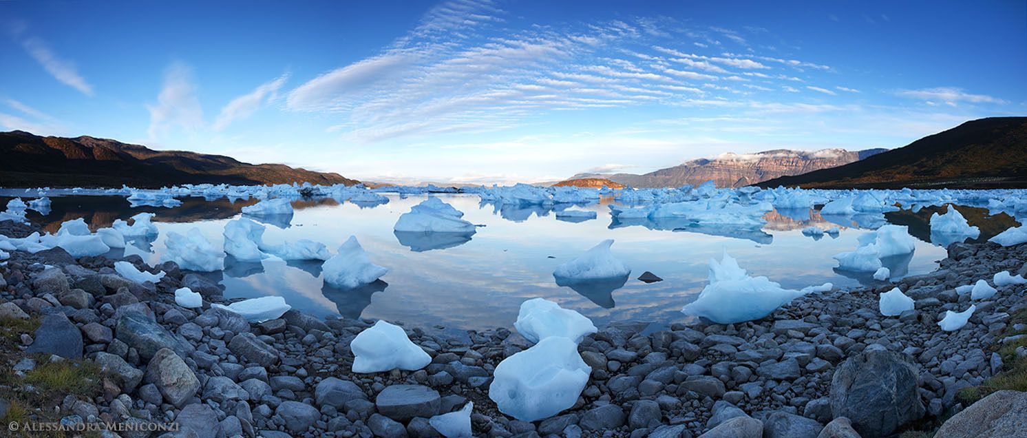 Following two days of strong foehn winds, numerous large chunks of ice are stranded ashore and grounded in shallow water in Sermilik Fjord, southeast Greenland.