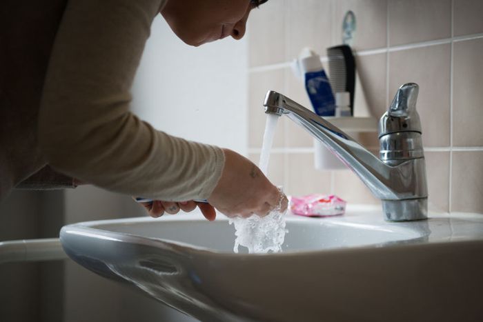 Sarah cleans her teeth in an apartment
