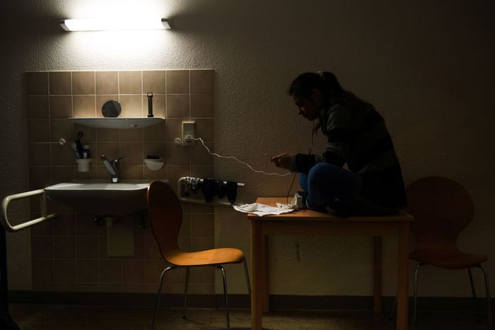 Sarah plays with her phone in her room in an apartment