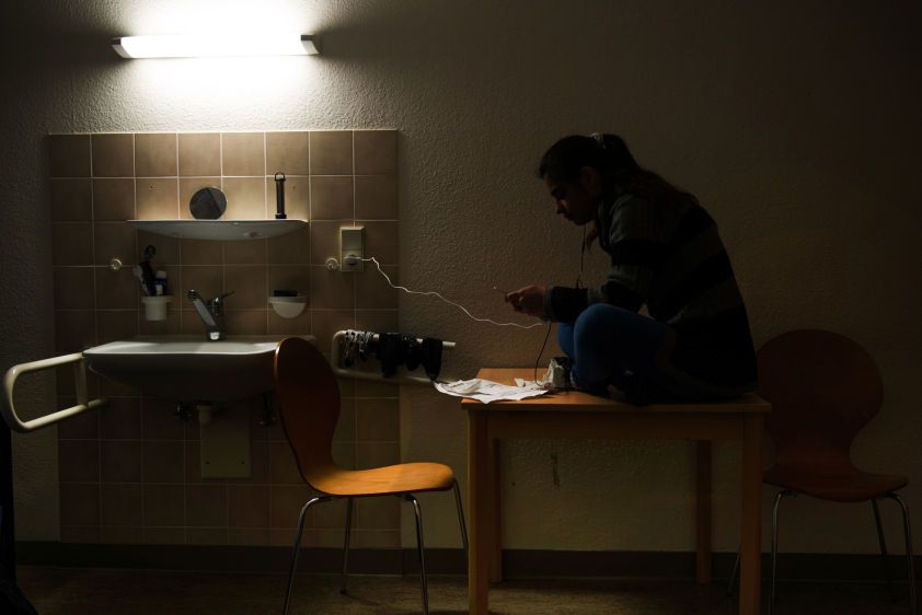 Sarah plays with her phone in her room in an apartment