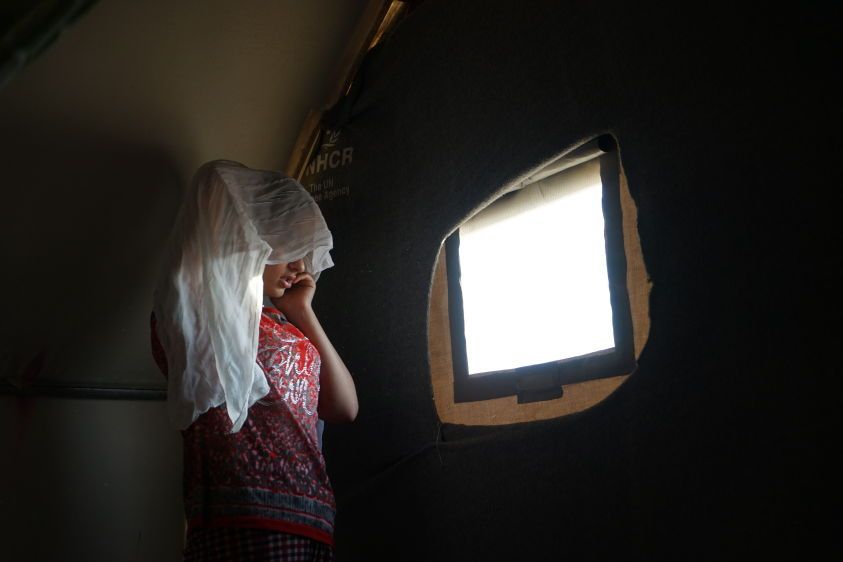Sarah (her name changed to protect her identity) speaks on the phone inside the tent where she is living with her family in a refugee camp in northern Iraq.