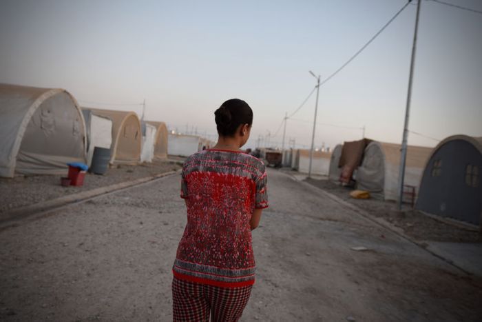Sarah walks between tents in a refugee camp in northern Iraq where she is living with her parents.