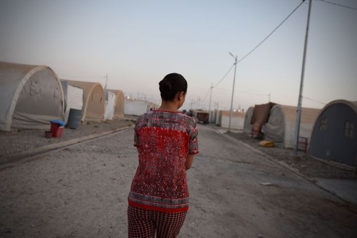 Sarah walks between tents in a refugee camp in northern Iraq where she is living with her parents.