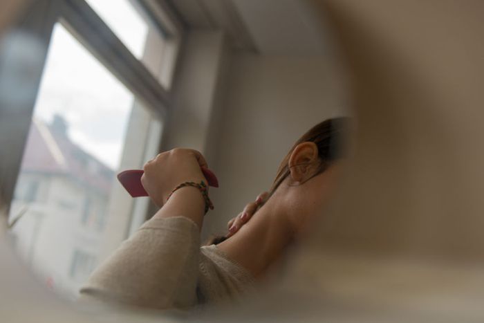 Sarah  combs her hair in her room in an apartment i