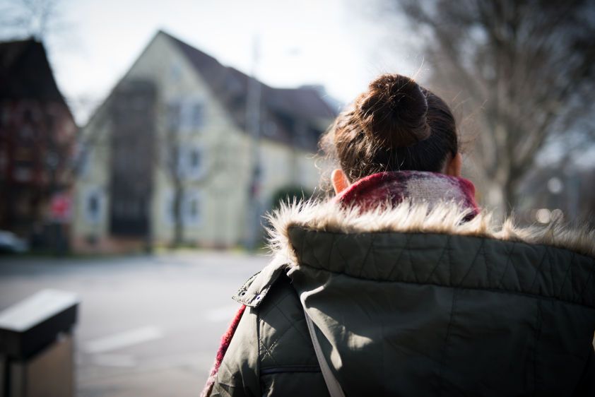 Sarah walks along a street in a German town