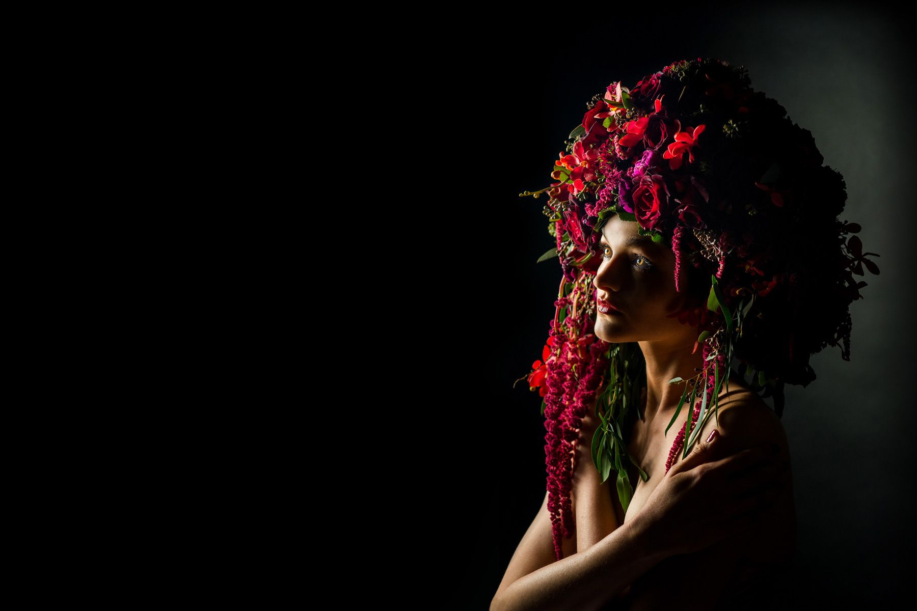 Fashion model wearing a red & crimson floral headdress.  In studio Photo Shoot.