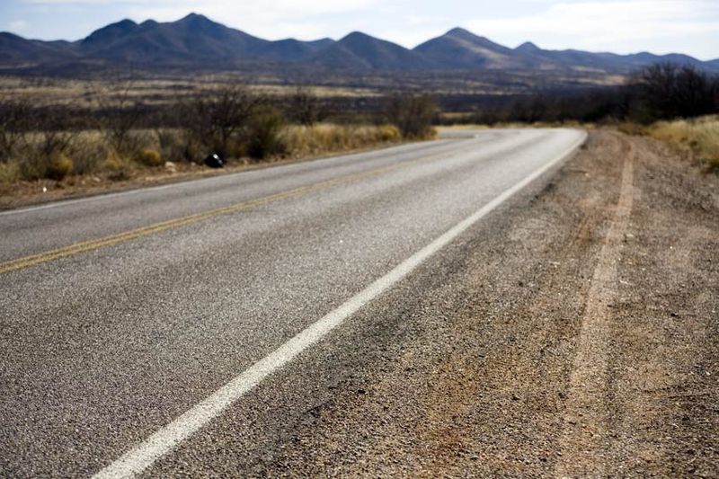 An early morning tire track at the side of the road is likely from a vehicle picking up migrants in the vast Arizona desert. The next stretch