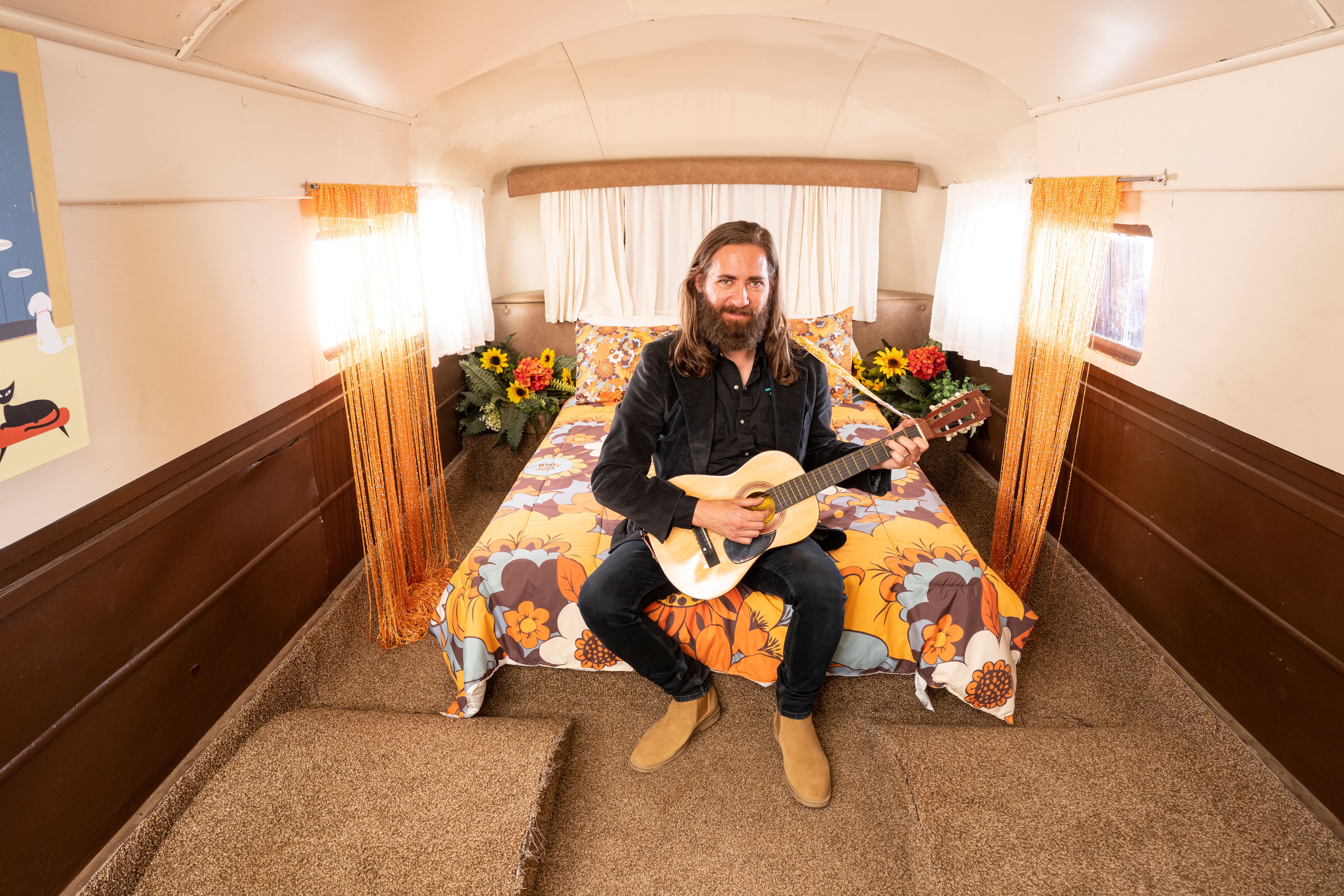 Guitarist on 70s style bed