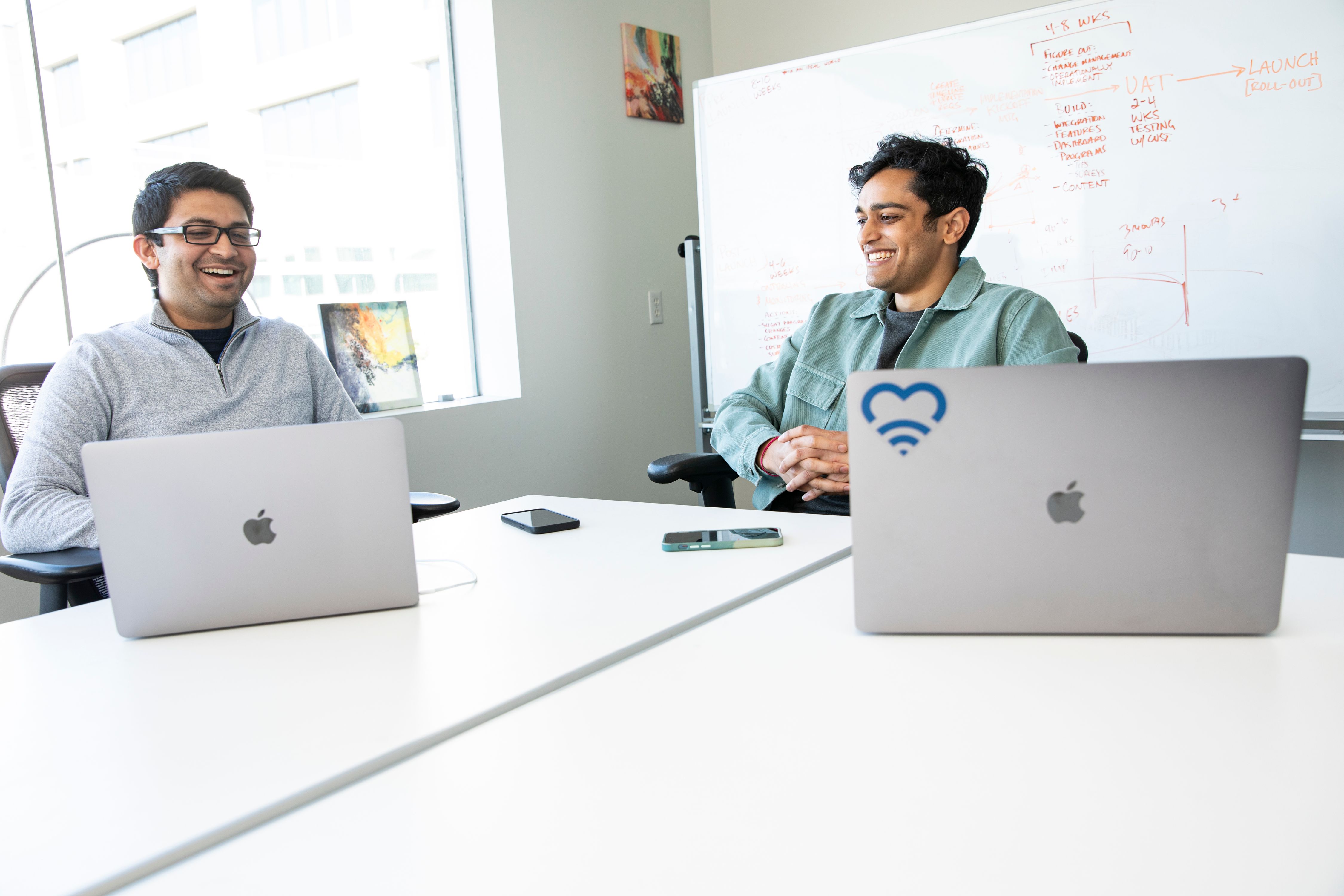 Two young start up founders laugh in a meeting 