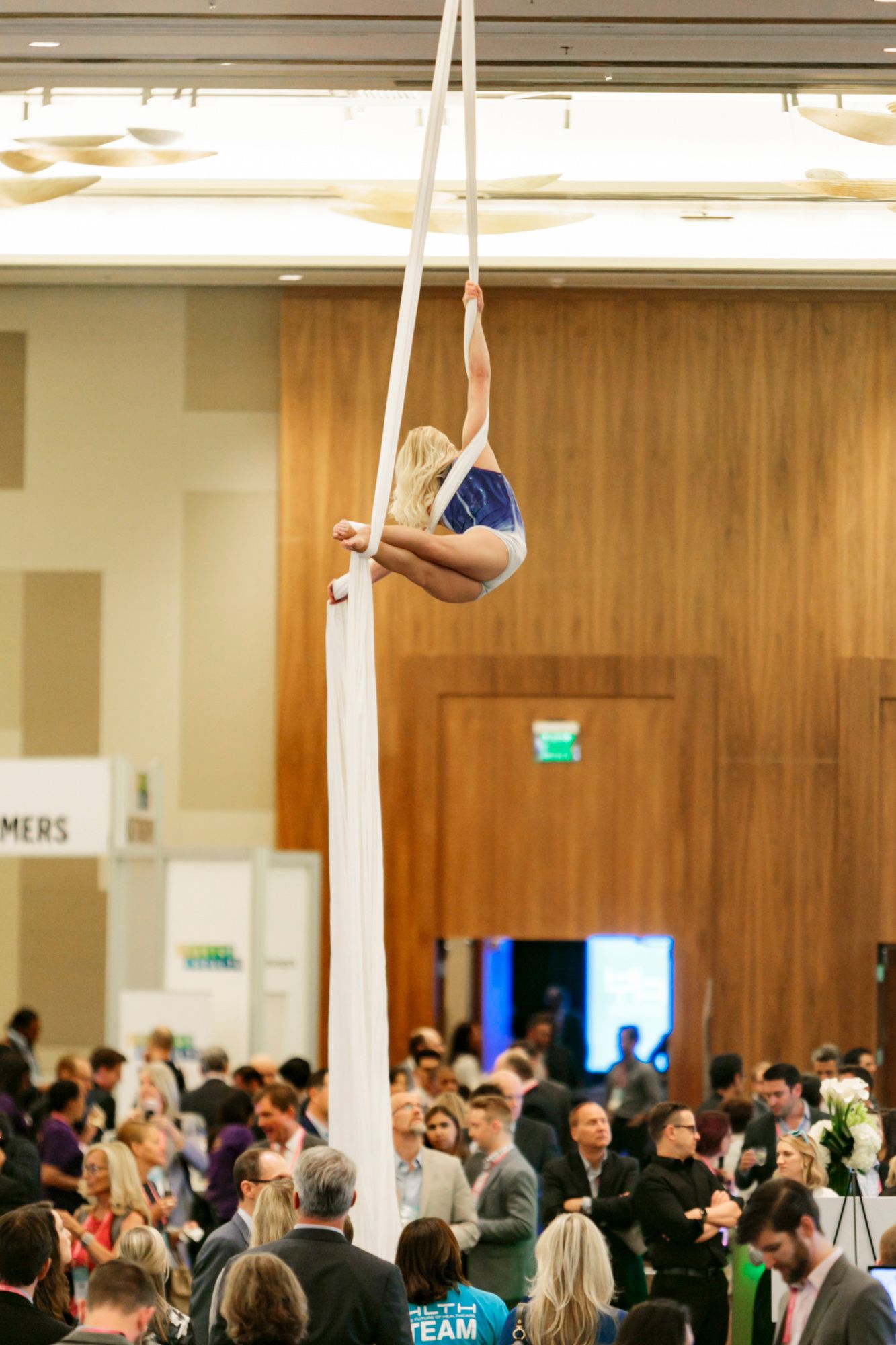 Female acrobat hangs from ceiling at Aria Convention Center