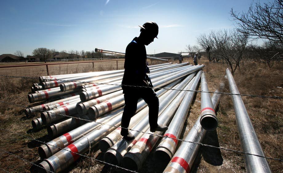 A gas field worker assesses a pile of pipes Laying natural gas pipelines