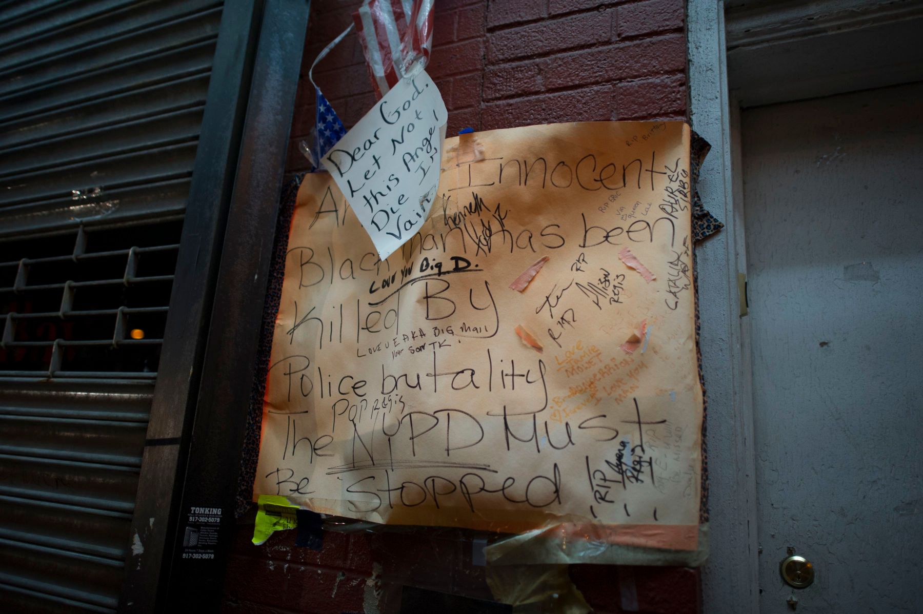 12/03/2014: A paper sign calling for Justice hung above the Eric Garner memorial on Bay Street in Staten Island. People gathered around the sight somberly, after hearing that a grand jury decided not to indict the officer who had killed Mr. Garner with an illegal choke hold. 1gjv_3357