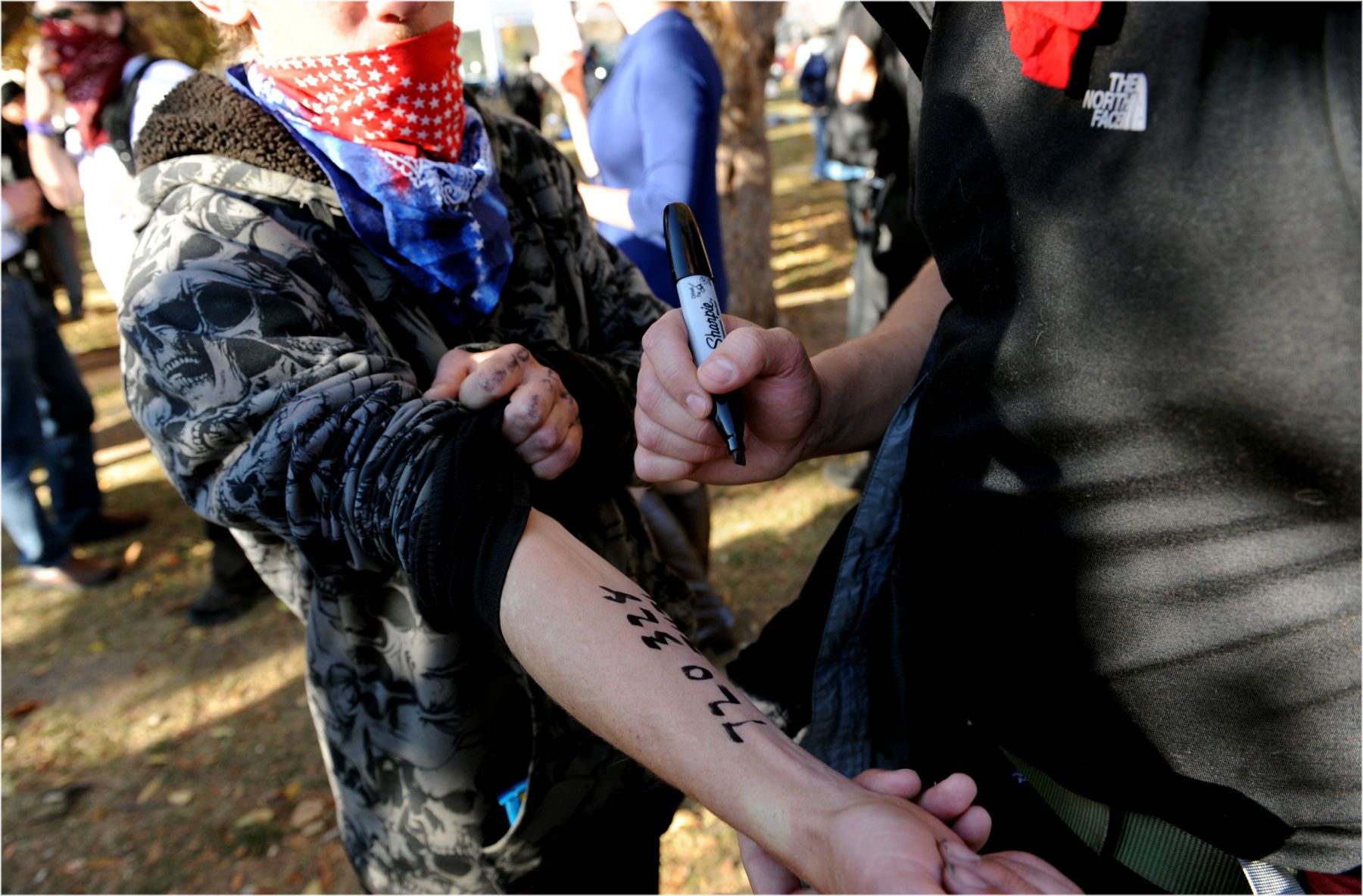 Occupy Denver demonstrators write legal aid contact numbers with permanent marker on their arms in case of arrest. 1phone_b