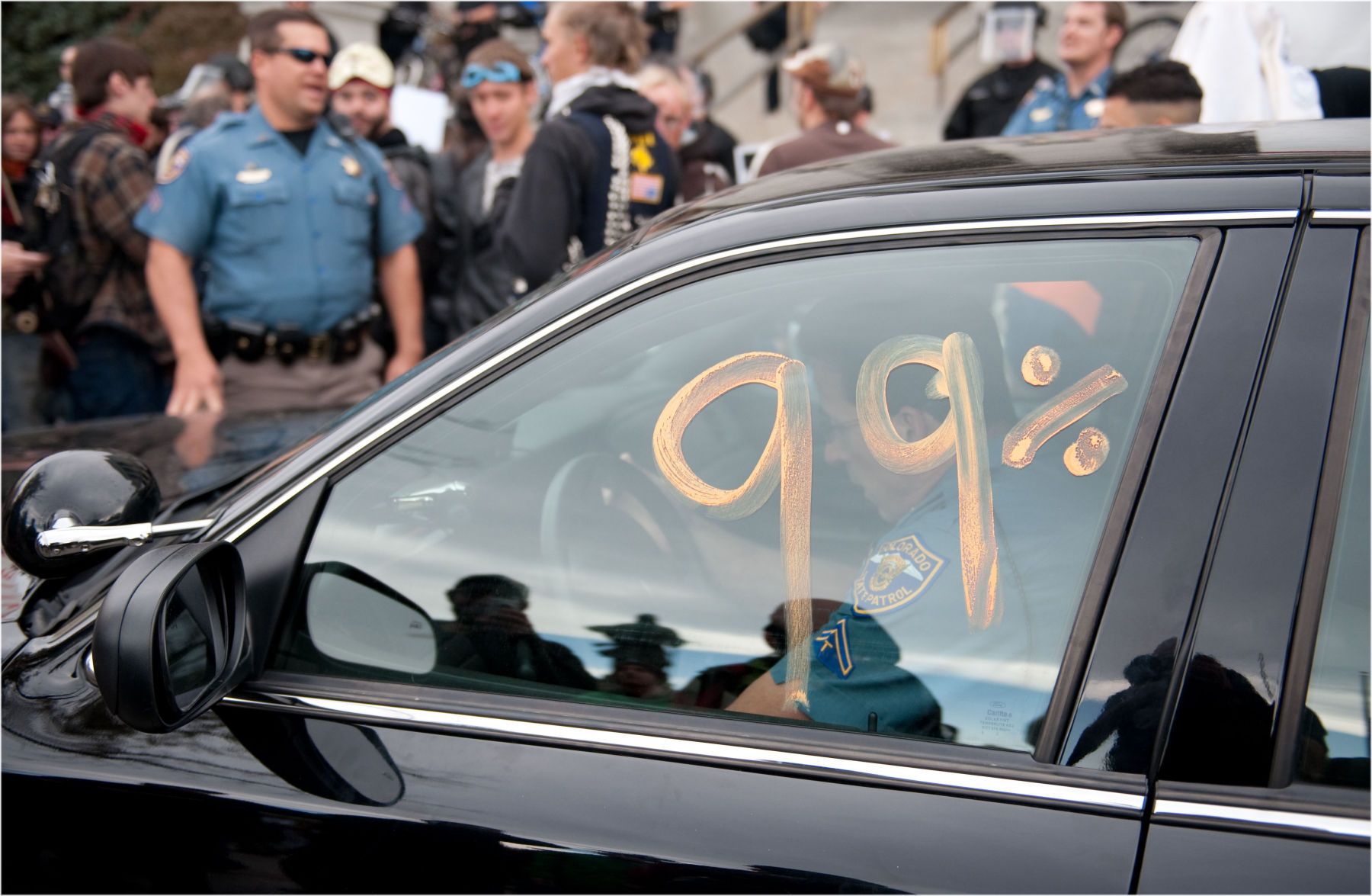 A Colorado State Patrol officer moves his vehicle after demonstrators painted it with 99%. 1r99_b