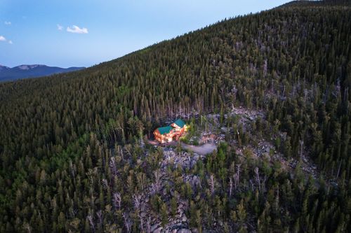 A twighlight real estate photo of a lone mountin home surrounded by forest at twighlight. Lone Twighlight Mountain Home