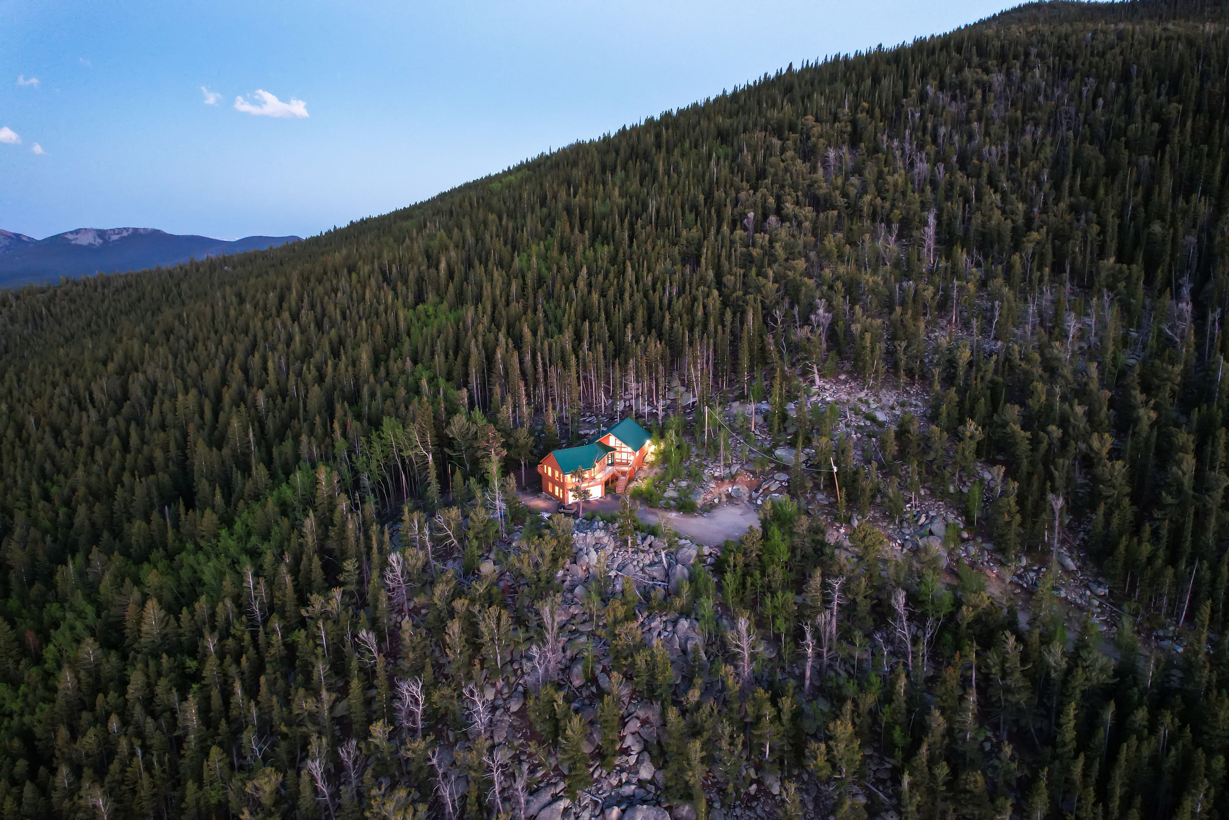 A twighlight real estate photo of a lone mountain home surrounded by forest. Lone Twighlight Mountain Home