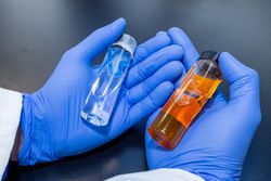 Sample bottles of before and after from a new extraction process. Hand Holding Samples