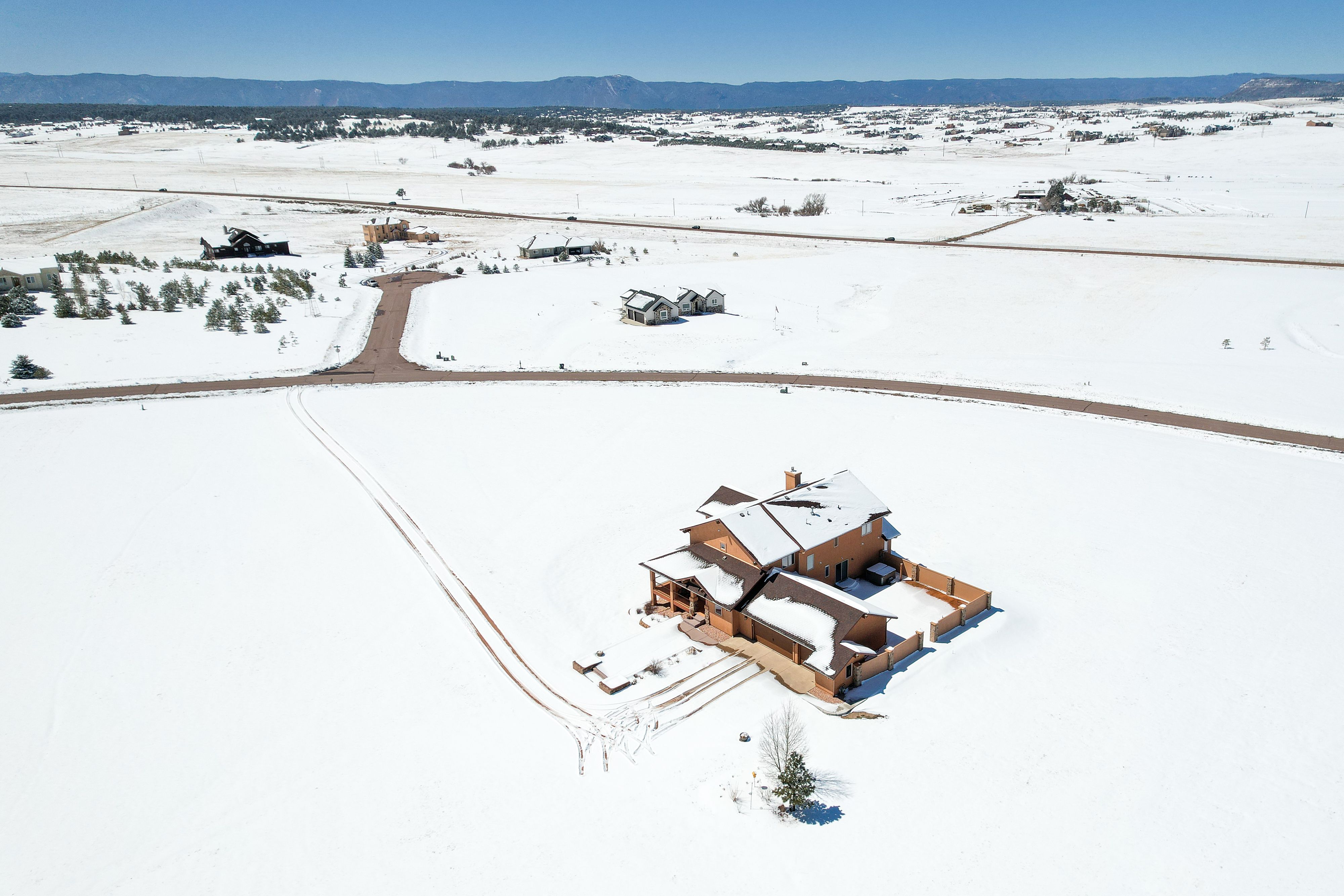 An aerial real estate photo made by a drone looking down on a winter snow covered landscape surrounding a country home. Winter Snow Hoestead