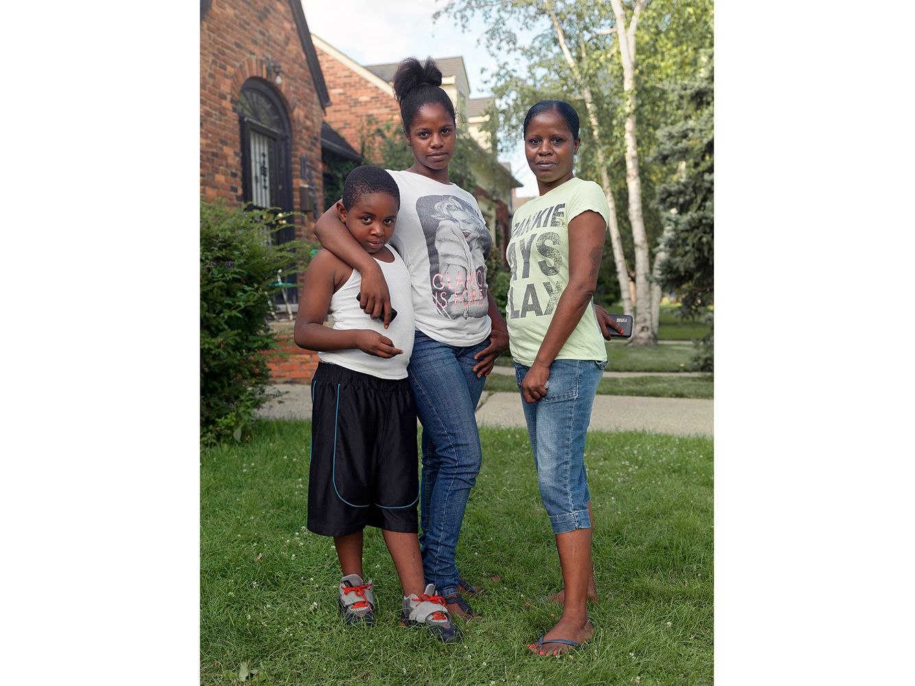 A mother with her daughter and grandson in the front yard of their house. Krystal, Jasmine, and Dalandis, Eastside, Detroit 2013